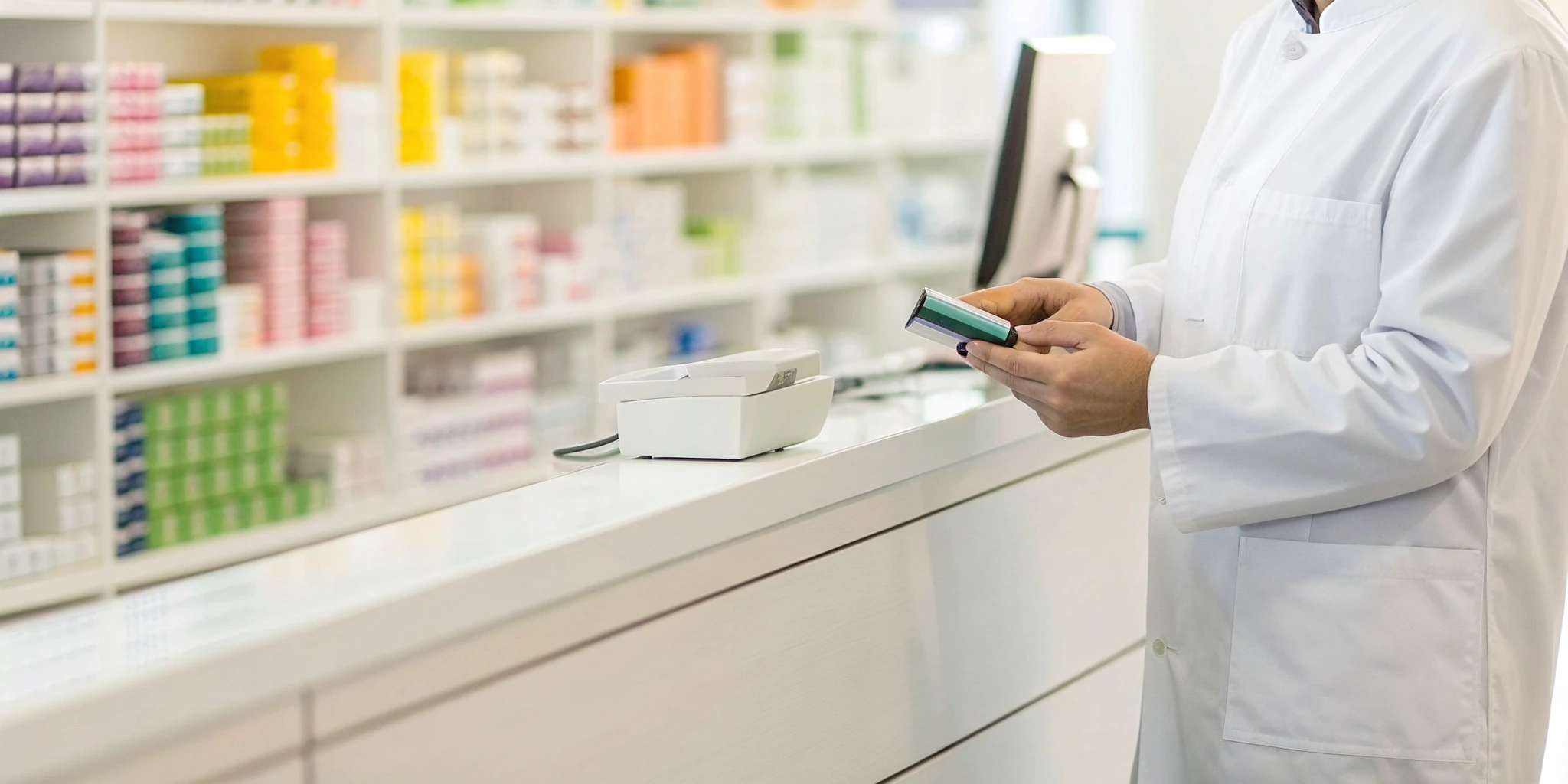 Pharmacist at a counter verifying medication to ensure DSCSA compliance for dispensers.